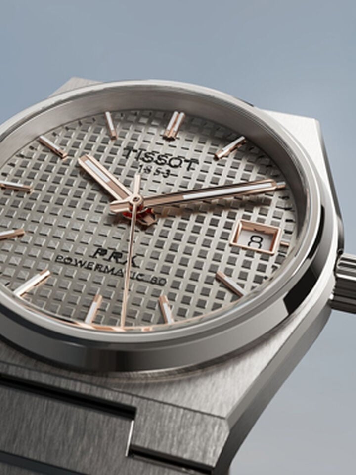 Close-up of the dial of the Tissot PRX 38mm Titan watch on a neutral grey background