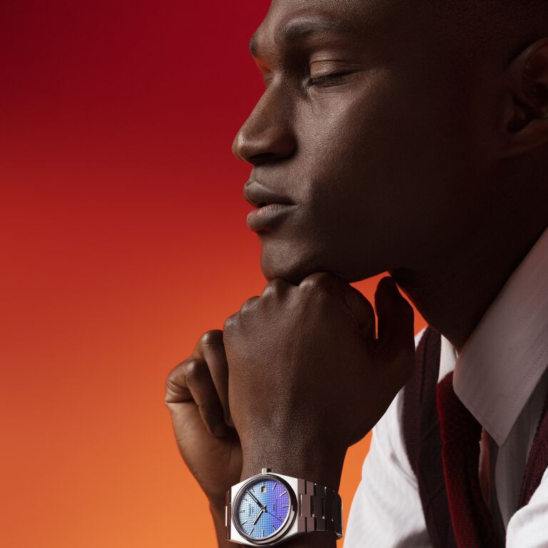 Model wearing a Tissot PRX watch with a sky-blue to purple gradient dial.