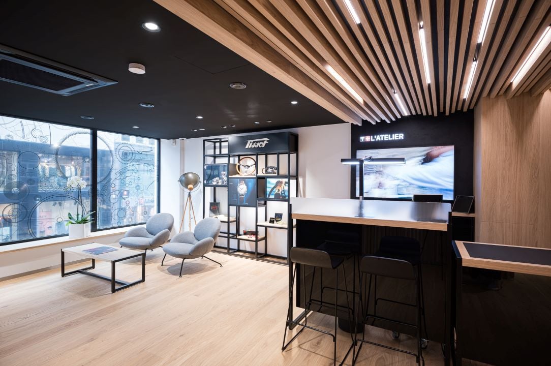 Innenansicht der Tissot-Boutique in Frankfurt, mit modernen Lounge-Sitzgelegenheiten, Regalen und einer Werkbank für Uhrenservices.