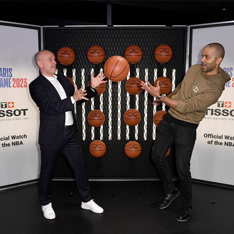 Tissot CEO Sylvain Dolla and basketball legend Tony Parker playfully tossing a basketball at a Tissot event. 