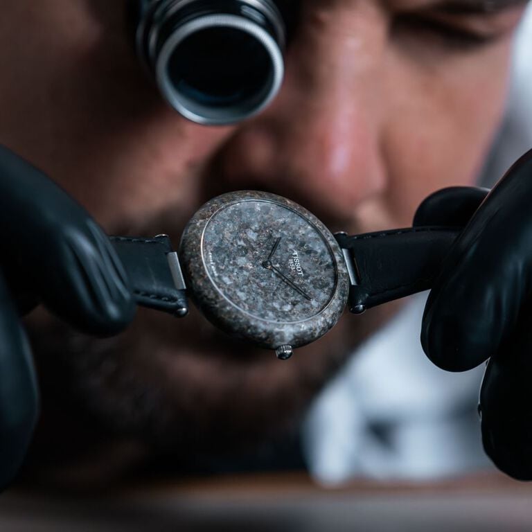 Enfoque en el Tissot RockWatch sostenido por un relojero, destacando sus detalles y acabados.