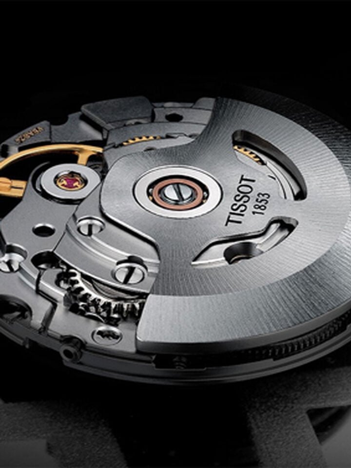 Close-up of the Tissot Powermatic 80 mechanical movement, showing the precise details of the gears and the metallic finish of the mechanism.