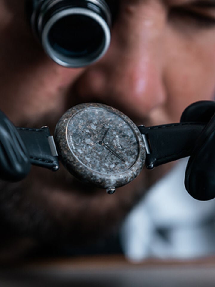 Focus on the Tissot RockWatch held by a watchmaker, highlighting its details and finish.