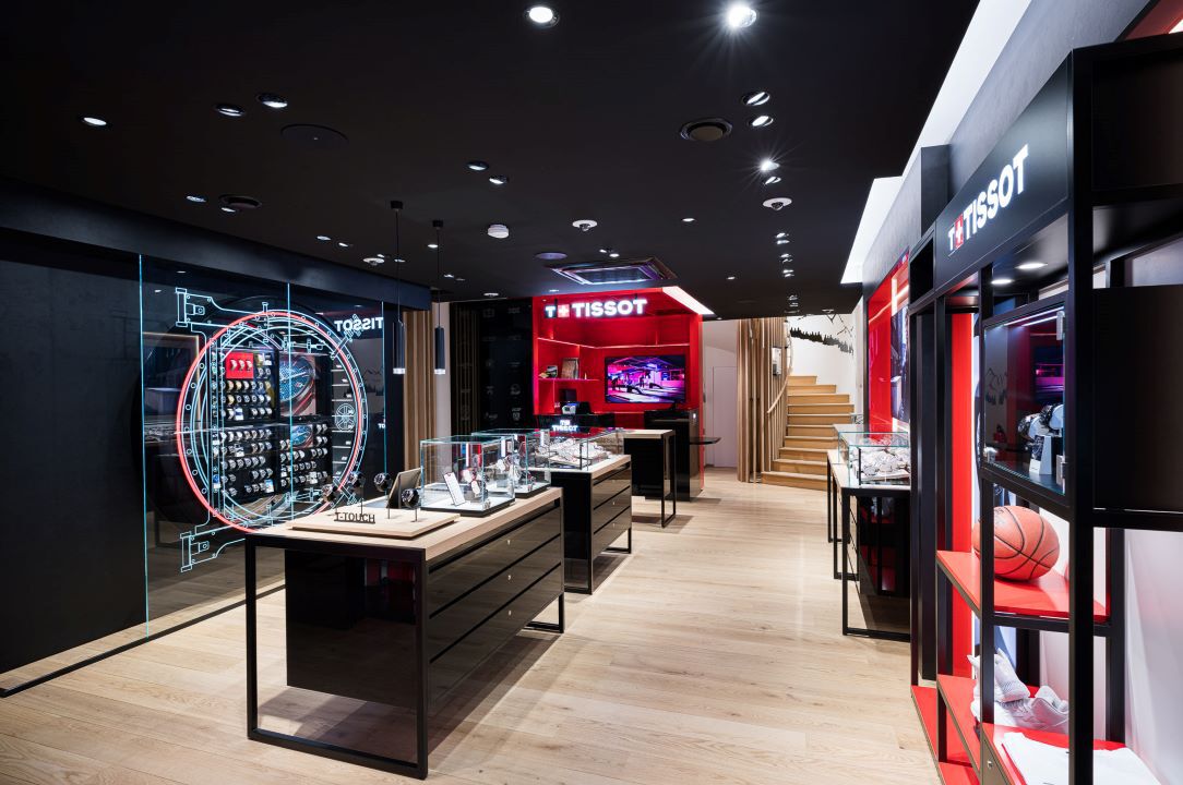 Innenansicht der Tissot-Boutique in Frankfurt, die verschiedene Uhrenkollektionen zeigt, mit eleganten Glasvitrinen und einem lebhaften rot-schwarzen Farbschema.