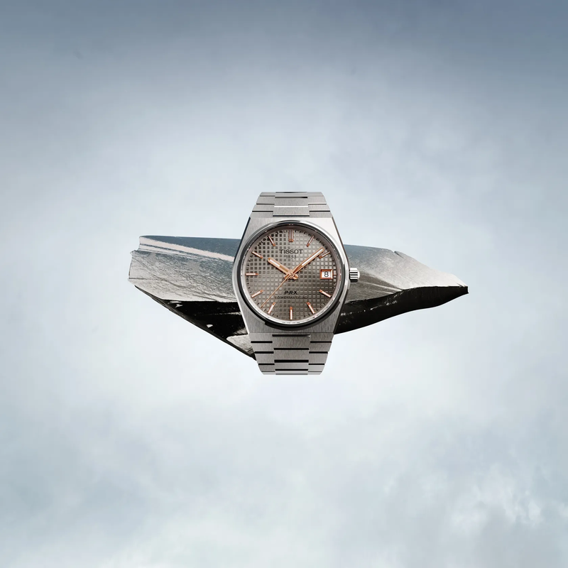 Tissot PRX Titanium 38mm watch on a coloured background