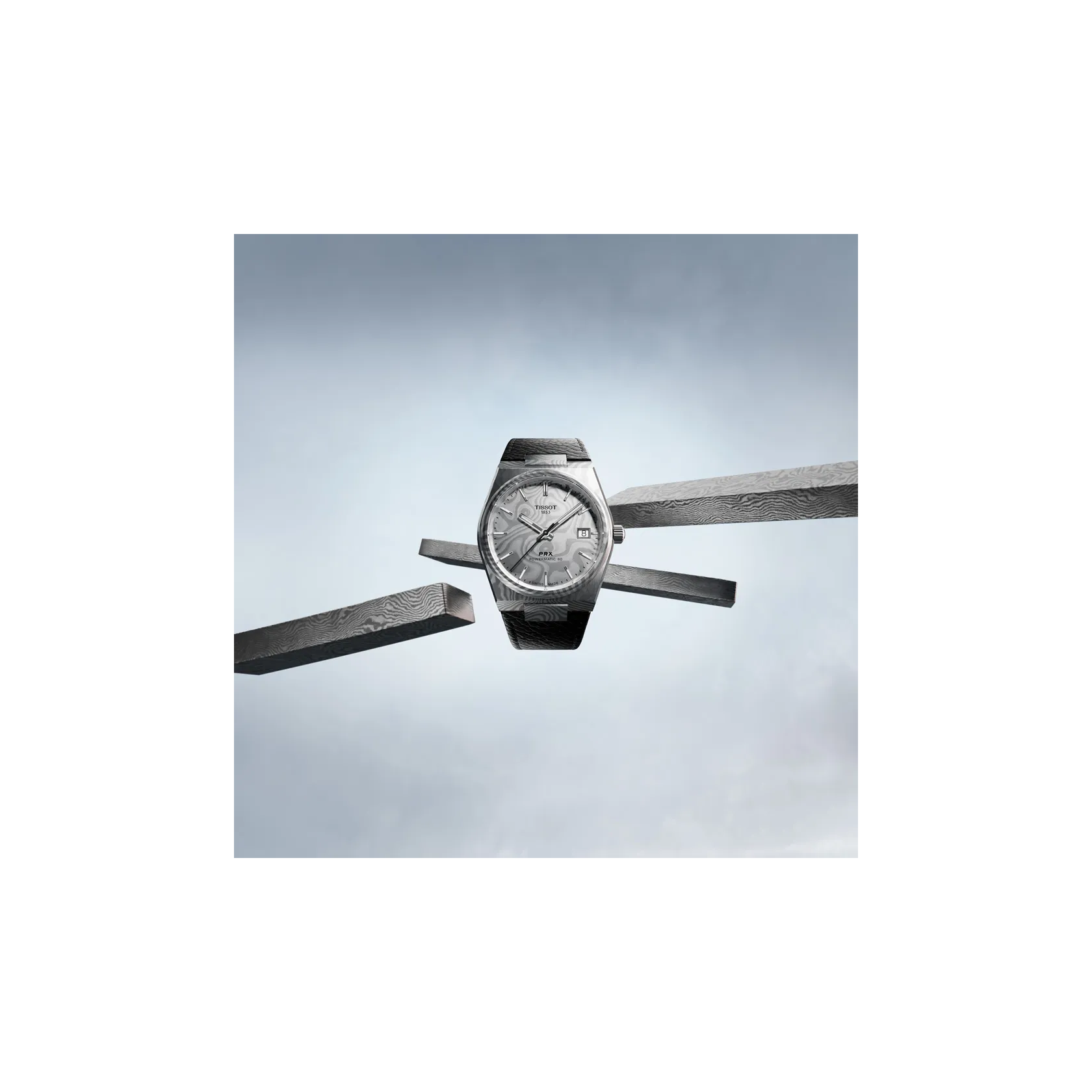 Tissot PRX Damascus Steel 38mm watch on a coloured background
