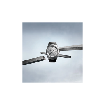 Tissot PRX Damascus Steel 38mm watch on a coloured background
