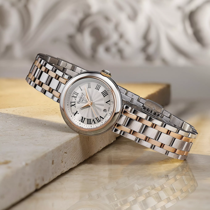 Tissot Bellissima 26mm watch on a colored background