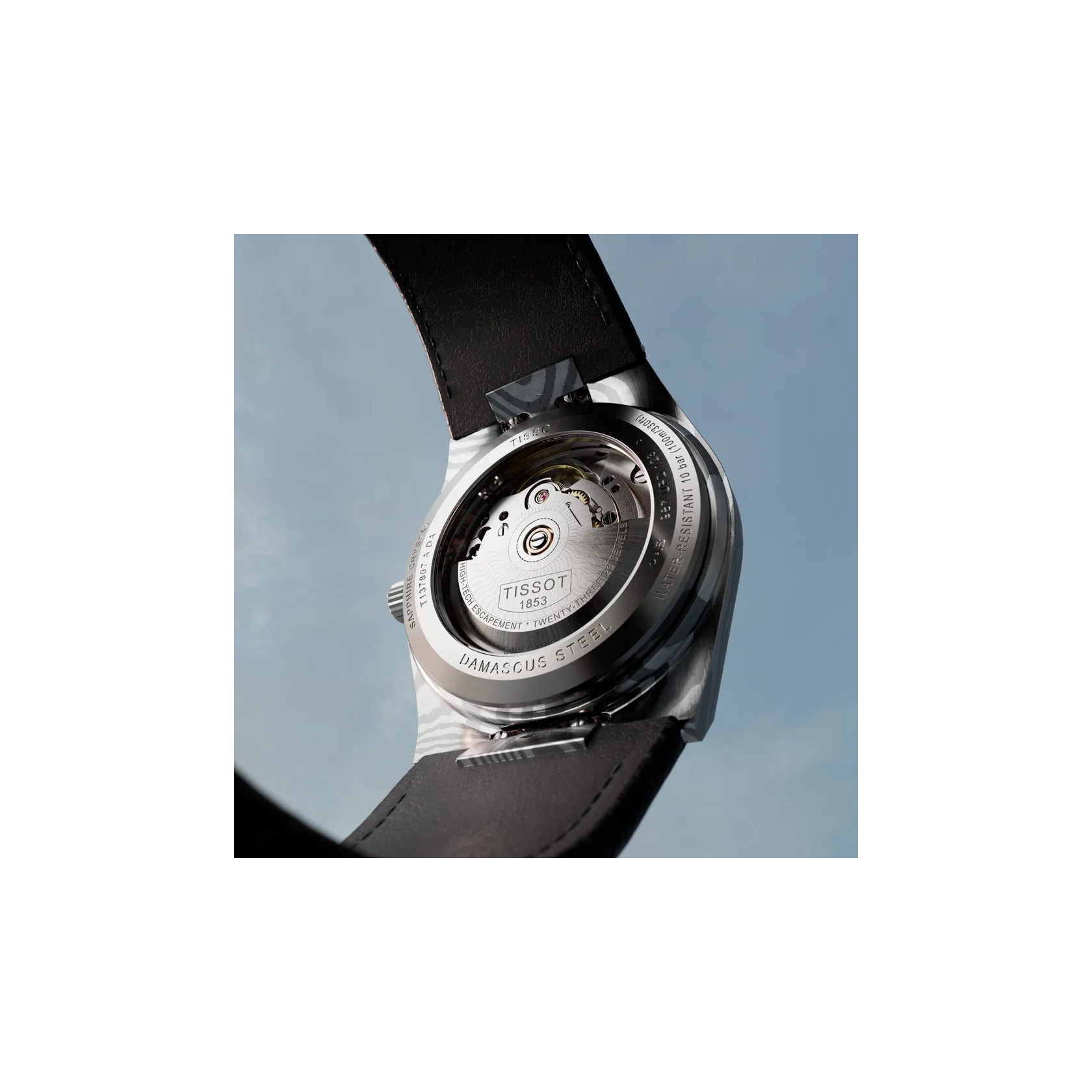 Tissot PRX Damascus Steel 38mm watch on a colored background