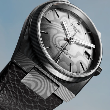Tissot PRX Damascus Steel 38mm watch on a coloured background