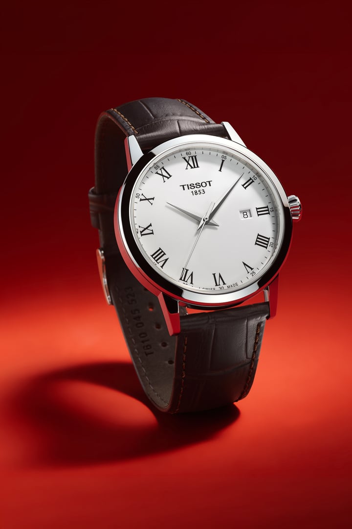 White dial watch with brown leather strap on red background