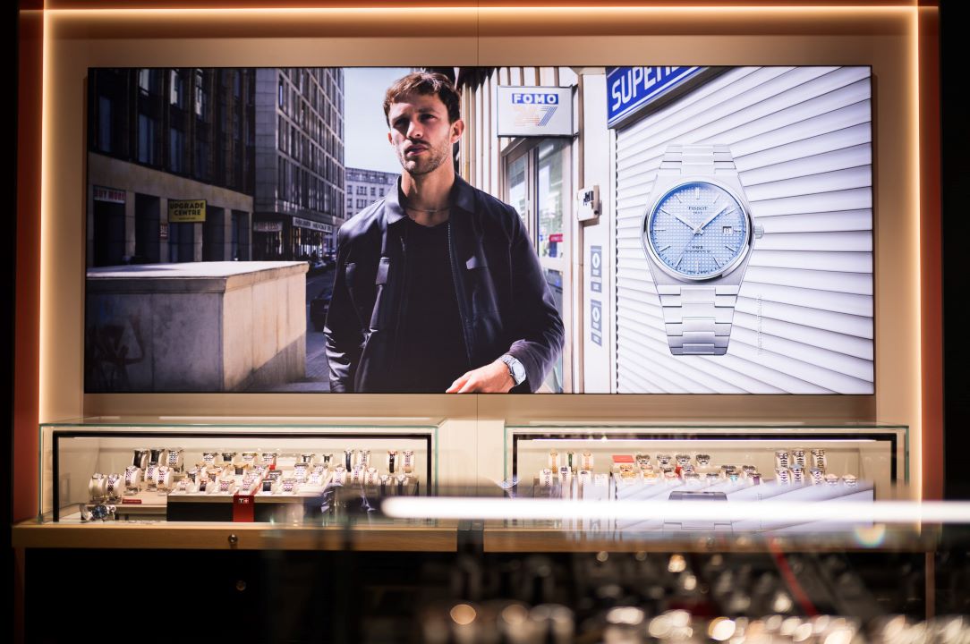 Eine Auslage mit einem Bild eines Mannes, der eine Tissot PRX-Uhr tr&auml;gt. Unter dem Bild befindet sich eine Glasvitrine mit verschiedenen Tissot-Uhren.