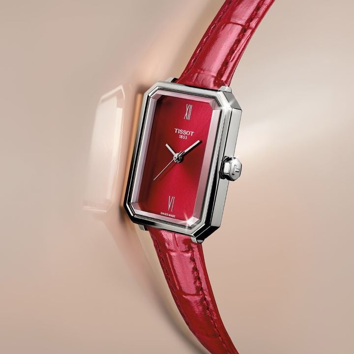 Tissot SRV watch with a steel case, red leather strap, and matching dial, presented on a beige background.