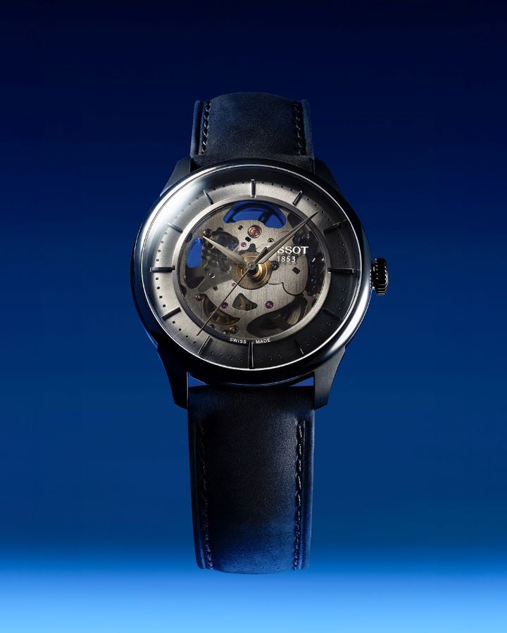 The new Tissot Chemin des Tourelles Squelette in ivory with leather strap, front view against a blue background