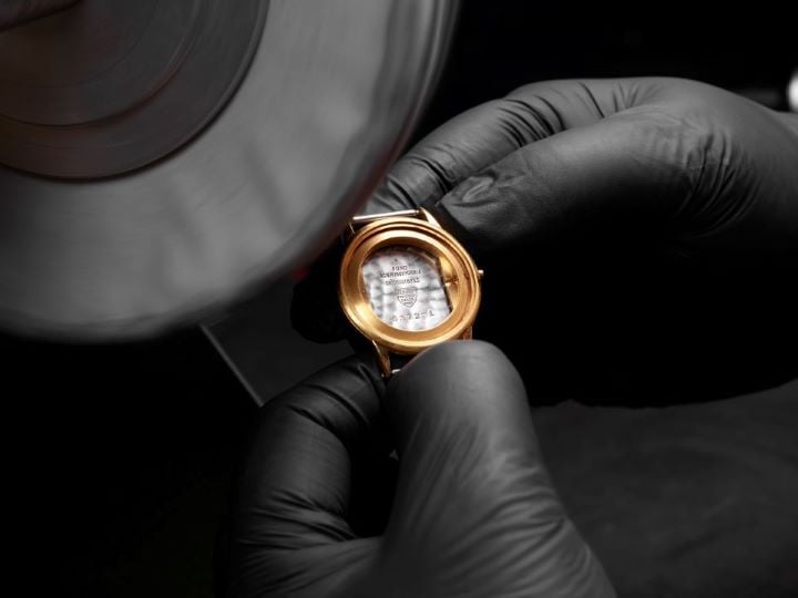 Gold case of a Tissot watch being polished.