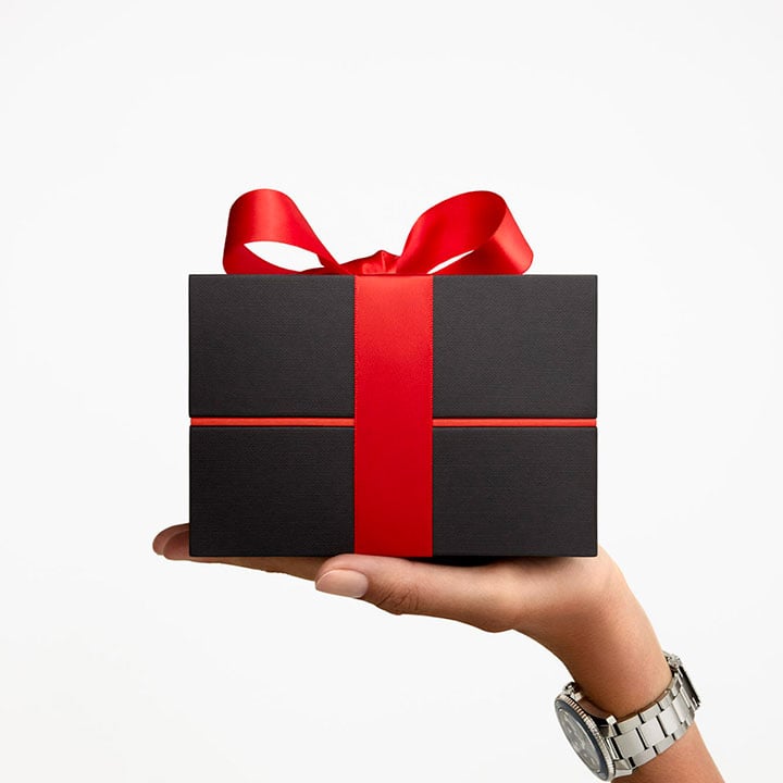 Women handing a gift package with a red ribbon
