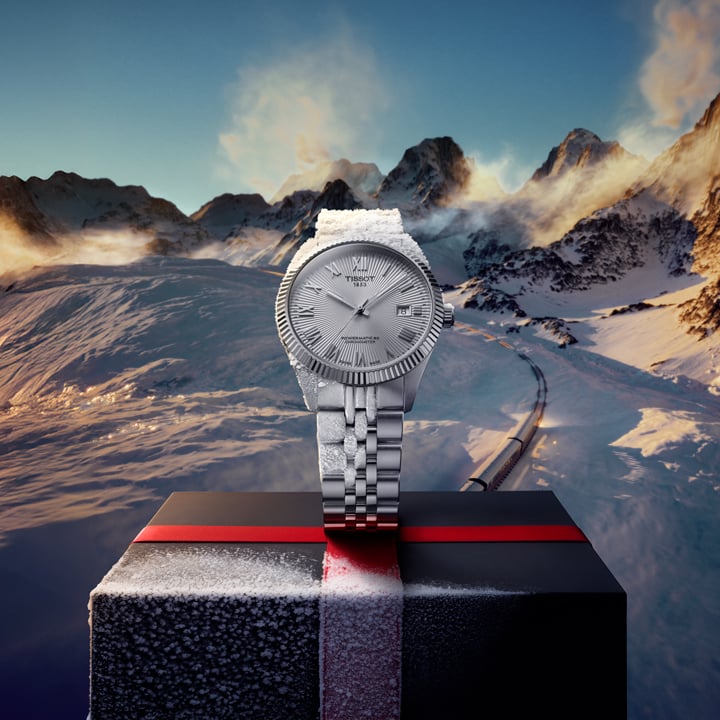 Man wearing a Tissot watch holding a wrapped gift box