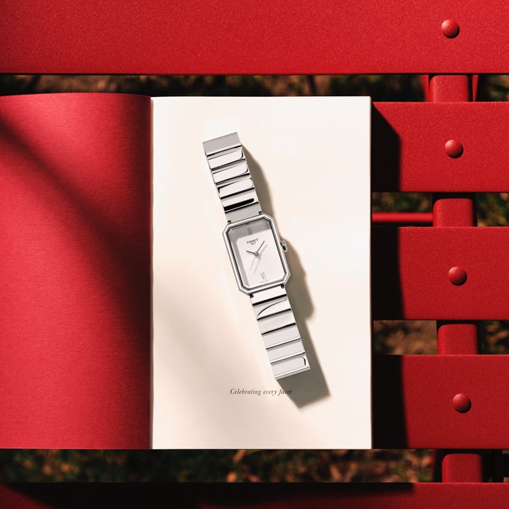 Tissot SRV steel with white dial on a book rested on a red outdoor chair 