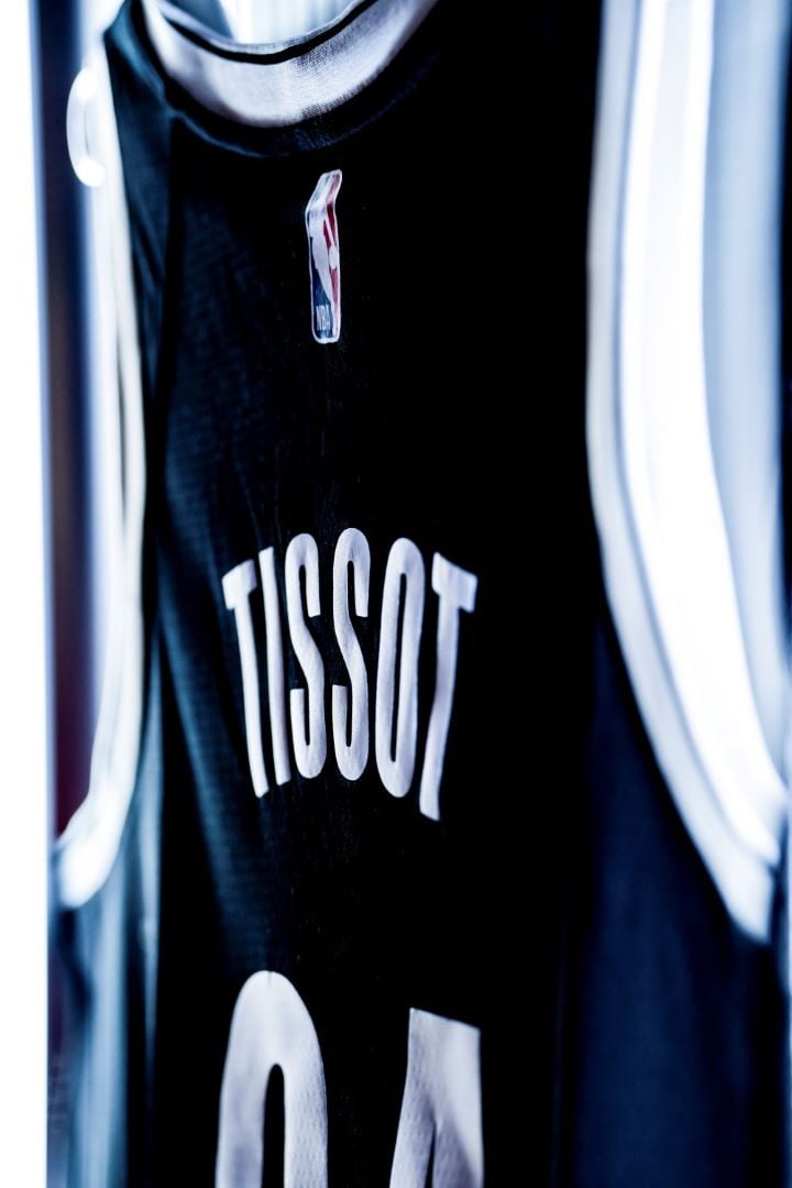 Image of the back of a blue and white basketball jersey bearing the Tissot name, number 04 and NBA logo.