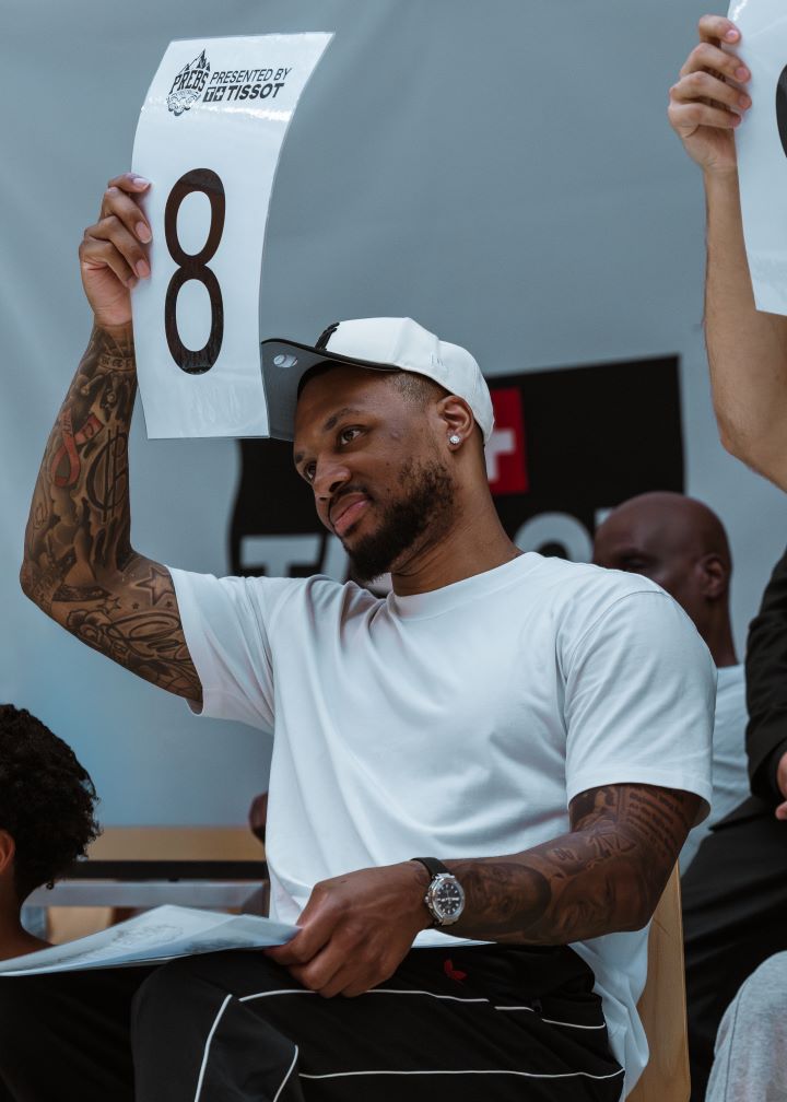 NBA Superstar Damian Lillard, holding up a sign with the number 8 to give a score.