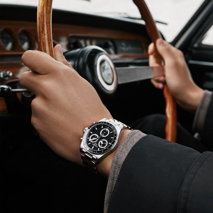 The new Tissot PR516 mechanical chronograph on the wrist of a man driving and holding the wheel of his car.