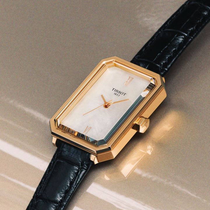 Tissot SRV watch with a black leather strap and grey dial, displayed on a beige car..