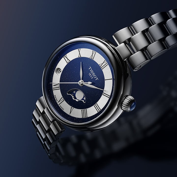 Close-up of a silver Tissot moonphase watch with a deep blue dial and Roman numerals.