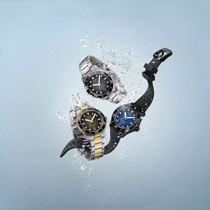 Trio zegark&oacute;w Tissot Seastar 1000 Powermatic 80 40mm w kolorze niebieskim, czarnym i dwukolorowym, otoczone bąbelkami.