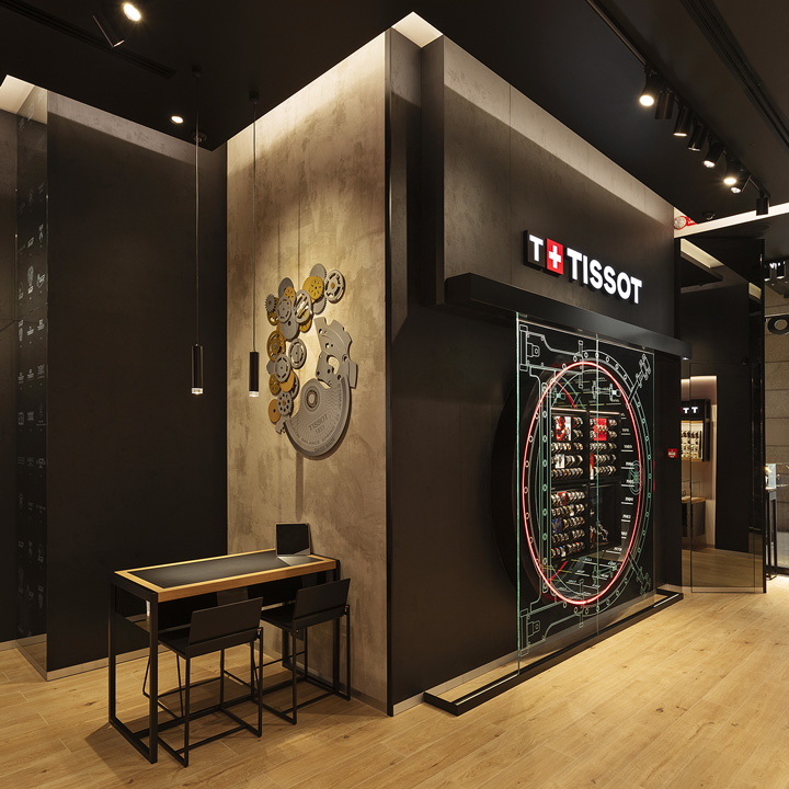 Angolo dedicato all&rsquo;esperienza cliente nella boutique Tissot a Milano, con un'area di consulenza elegante e installazioni artistiche ispirate ai movimenti orologieri