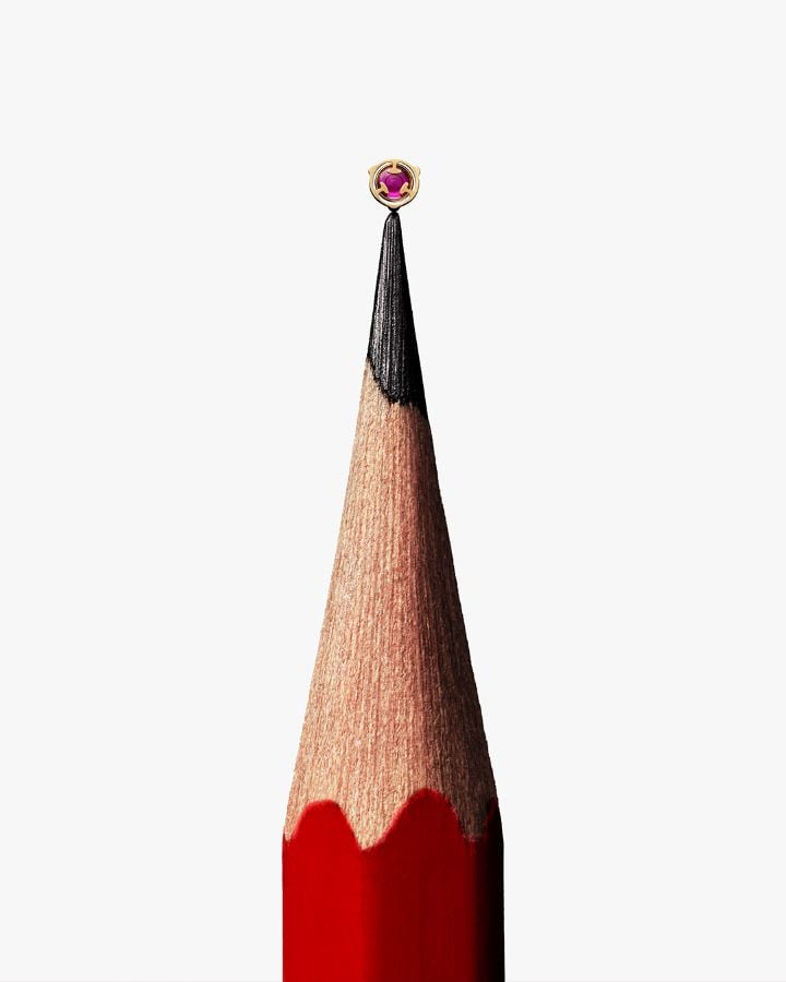A synthetic ruby, a component of the Tissot Powermatic 80 movement, placed on the tip of a pencil, illustrating its small size.