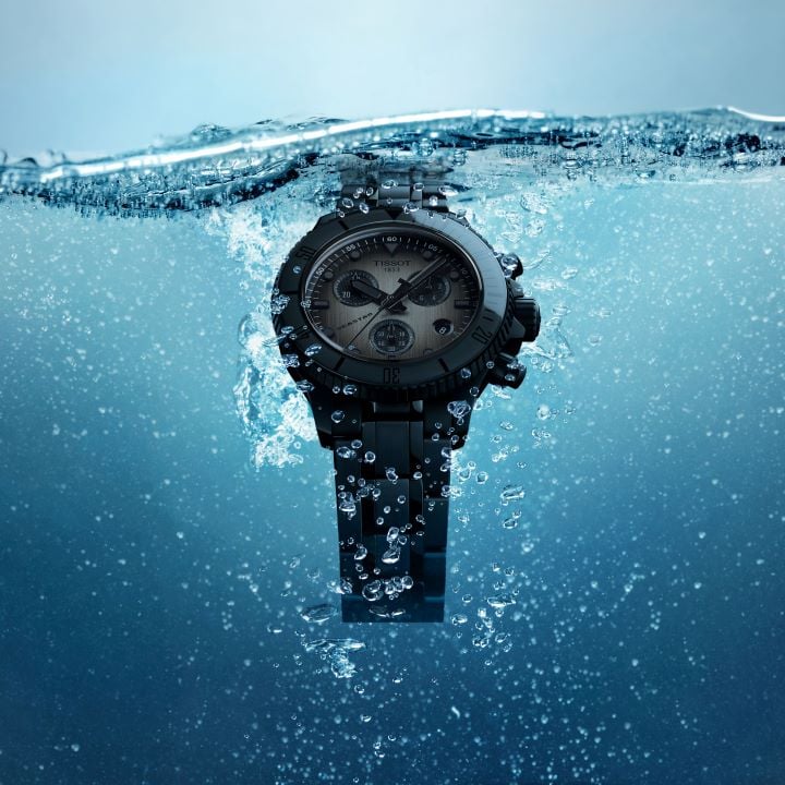 The black Tissot Seastar 38mm is partially immersed in water, with bubbles rising to the surface, highlighting its elegant design and performance in an aquatic environment.