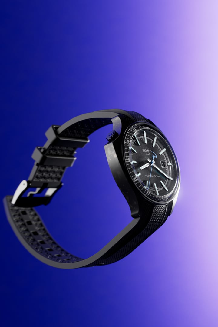 Seitliche Ansicht einer Tissot Pinarello mit dunklem Zifferblatt und Kautschukarmband vor einem lila-blauem Hintergrund.