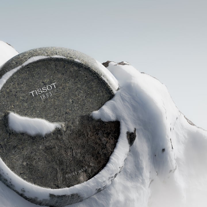 Close-up of a Tissot RockWatch dial carved from granite, partially covered in snow, with the inscriptions &ldquo;Tissot 1853&rdquo; and &ldquo;Swiss Made&rdquo; visible