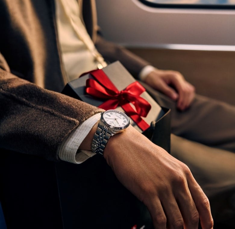 Man wearing a Tissot watch holding a wrapped gift box